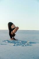 Fitness yoga woman stretching on sand. Fit female athlete doing yoga pose. photo