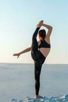 Fitness yoga woman stretching on sand. Fit female athlete doing yoga pose. photo