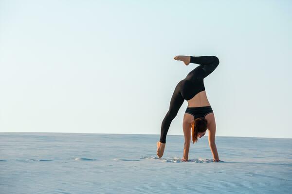 Fitness Yoga Woman Stretching On Sand. Fit Female Athlete Doing