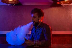 The man smoke an electronic cigarette at the vape shop. photo