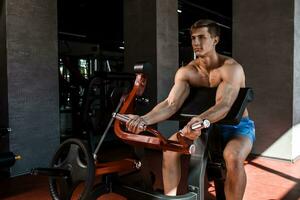 Tense muscles of hands under load. Man doing exercise for biceps in the gym. photo