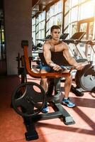 Tense muscles of hands under load. Man doing exercise for biceps in the gym. photo