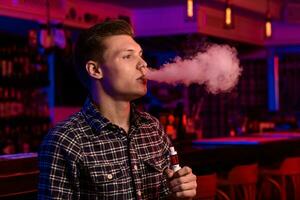 The man smoke an electronic cigarette at the vape shop. photo