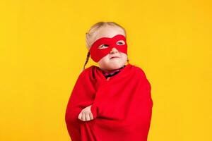 gracioso pequeño poder superhéroe niño niña en un rojo impermeable y un mascarilla. superhéroe concepto. foto