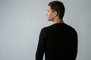 Back view of man in black sweater. Standing young guy. Rear view photo