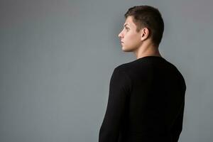 Back view of man in black sweater. Standing young guy. Rear view photo