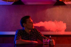 The man smoke an electronic cigarette at the vape shop. photo