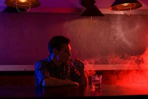 el hombre fumar un electrónico cigarrillo a el vape tienda. foto