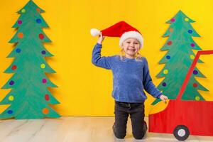 Child with Christmas hat driving a car made of cardboard. Christmas concept. New Year's holidays. photo