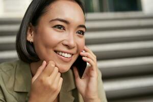 Close up portrait of asian girl talks on mobile phone. Young woman having a phone call, using her telephone photo