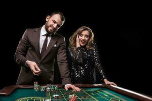 Man and woman playing at roulette table in casino photo