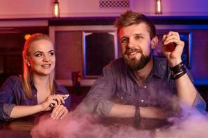 A man and woman smoking electronic cigarette in a vape bar. photo