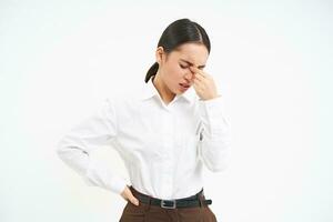 Asian office lady with tired face, rubs her eyes after working, feeling exhausted, standing over white background photo