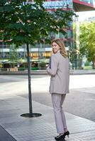 Portrait of businesswoman walking on street of an empty city center, holding folder with work documents photo
