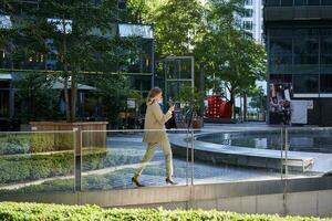 silueta de corporativo mujer en traje caminando a lo largo ciudad centrar cerca oficina edificios foto