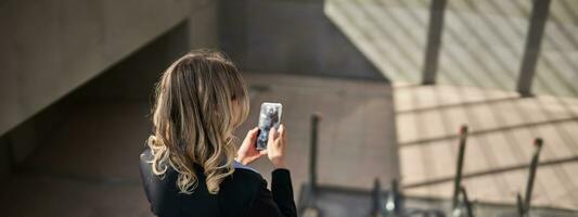 Portrait of corporate woman standing on escalator, making a phone call, using smartphone, walking in city photo