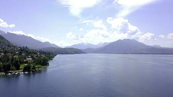 Panorama of lake, mountains and cottages near shore. Action. Top view of picturesque blue lake, shore with cottages for country holiday in summer and mountains on horizon photo