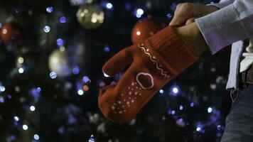 untado fuera mano en rojo de lana guante en Navidad fondo, concepto de alegría en invierno tiempo. hombre vistiendo un Navidad mitón en el mano foto