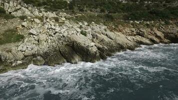 el olas rotura en un pedregoso playa, formando un rociar. imágenes. salpicaduras olas en el rocas de el mar foto