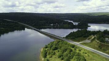 A huge bridge across the river. Clip. Bird's-eye view. A huge bridge over a large river against the background of a cloudless sky and huge forest trees. photo