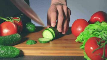 hombre rebanar Pepino mientras mujer roba otro vegetales desde el mesa. fuerte impaciencia para comiendo. familia gracioso Cocinando concepto. de cerca disparo, estático ver video