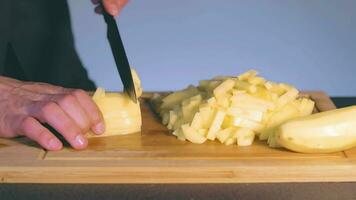 chefe de cozinha dentro Preto uniforme é fatiamento cru batata. homem dentro uma cozinha é corte batata e preparando ingredientes para cozinhando lento movimento. estático tiro video