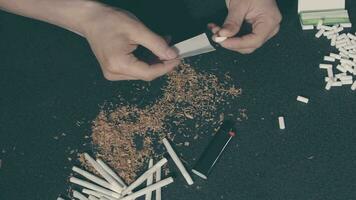 Man in Black Clothing is Rolling a Hand Made Cigarette Using Papers, Filters and Tobacco. A Way to Save on Tobacco Products. Tobacco Product Economy Concept. Top View video