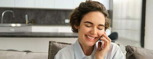 Close up portrait of happy, smiling beautiful woman laughing over the phone call, calling someone, having funny conversation on mobile, using smartphone to talk to friend photo