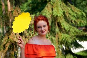 Young red haired woman in a red dress with a flyer for text in nature photo