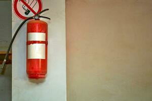 Fire extinguisher on the wall in the basement with a no smoking sign photo
