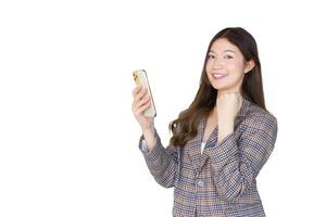 Young professional office Asian woman with black long hair wearing plaid suit while she acts enjoy with success of work using smartphone while isolated on white background. photo