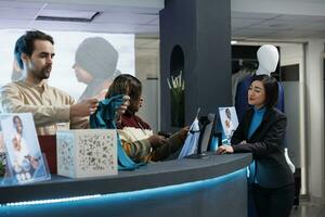 Fashion boutique smiling diverse employees scanning and packing clothes for client. Young asian woman making garment purchase at counter desk while shopping in fashion store photo