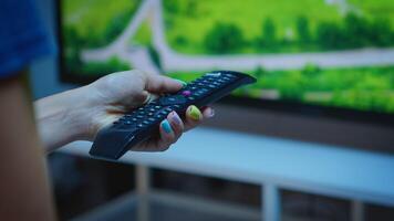 Lady holding TV remote control and pressing the button. Close up of woman hand changing TV channels sitting on comfortable couch in front of television using controller for choosing a movie photo