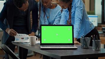 People using laptop with green screen on table, having isolated copyspace display in meeting to review annual data reports. Startup team checking papers, working with blank mockup. Tripod shot. photo