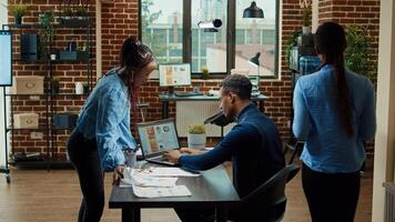 Coworkers discussing about reports plan to create new business vision for development, using annual data results and statistics in office. People examining analytics for collaboration. photo