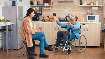 Handicapped man in wheelchair having a dispute with wife in kitchen. Guy with paralysis handicap disability handicapped difficulties getting help for mobility from love and relationship photo