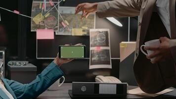 Team of law inspectors analyzing greenscreen display in private investigation archive room, working with copyspace and mockup template. Two detectives looking at chroma key screen. photo