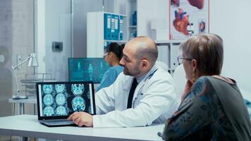 Doctor explayning how to reduce the risck of alzheimer for elderly patients, presenting a brain CT. Brain diagnosis, medical image CT, MRI or X Ray results in modern private hospital or clinic. Radiologist radiology healthcare system photo