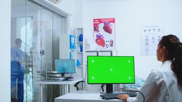 Nurse in blue uniform leaving hospital cabinet and doctor using computer with replaceable display. Computer with repleceable screen used by medicine specialist in hospital and wearing uniform. photo