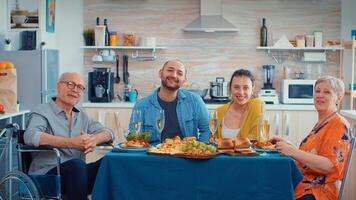 extendido familia y inmovilizado abuelo teniendo un vídeo llamada en su moderno, lujo cocina durante cena. pov en línea Internet moderno, charlando, comunicación, charla conversacion llamada vía cámara web. foto