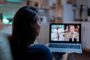 Woman talking with business people on webcam. Remote worker having online meeting, video conference consulting with colleagues on videocall working in front of laptop at home lying on couch photo