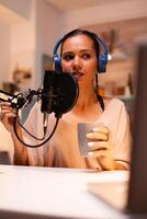 Talking on professional microphone during vlog recording in kitchen. On-air online production internet broadcast show host streaming live content, recording digital social media communication photo