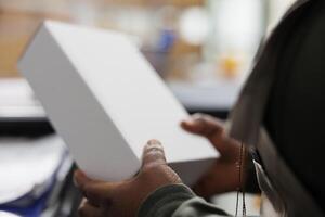 Stockroom employee holding white cardboard boxes, checking products before shipping packages in storehouse. Storage room manager working at clients orders during merchandise inventory photo