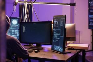 Hacker running malware code and launching ransomware on computer screen. Criminal working with illegal malicious software displaying on multiple monitors in dark room at night photo