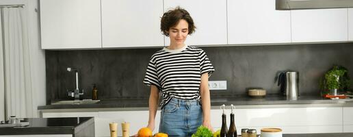 Portrait of young woman cooking salad. Cute girl vegan chopping vegetables on kitchen counter, preparing food photo