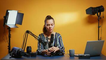 Social media star presenting a fluid tripod head in her professional studio. Influencer making online internet content about video equipment for web subscribers and distribution, digital vlog photo