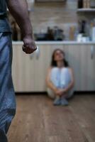 Close up of clenched fist of aggressive man after abusing woman, during domestic violence and physical trauma. Violent husband threatening helpless hurt wife with bruises on face photo