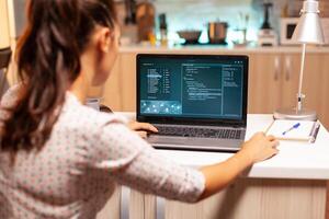 Female hacker sitting in front of computer and thinking how to fraud the government at night time. Programmer writing a dangerous malware for cyber attacks using performance laptop during midnight. photo