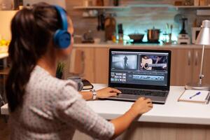 Young sound engineer working on video footage during post production. Content creator in home working on montage of film using modern software for editing late at night. photo