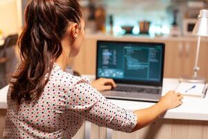 Hacker woman stealing people money using a malicious virus . Programmer writing a dangerous malware for cyber attacks using performance laptop during midnight. photo